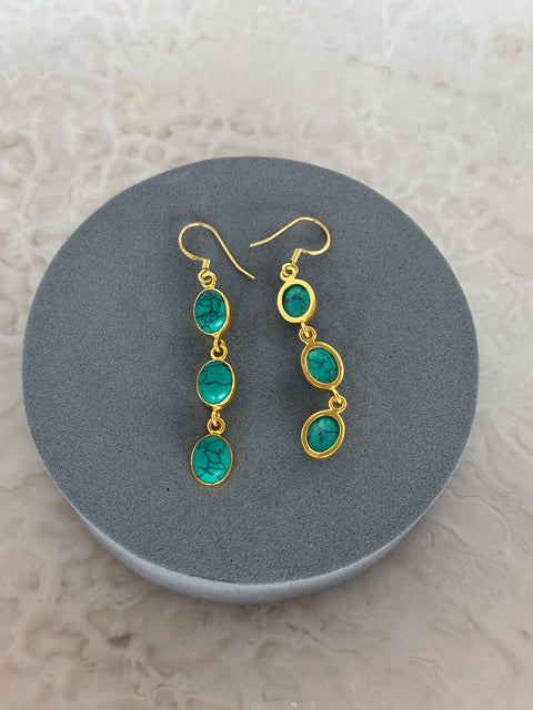 Angled Shot of Zara Gold Plated Sterling Silver with 3 Chain Linked Turquoise Gems Earrings on Soft Pillow