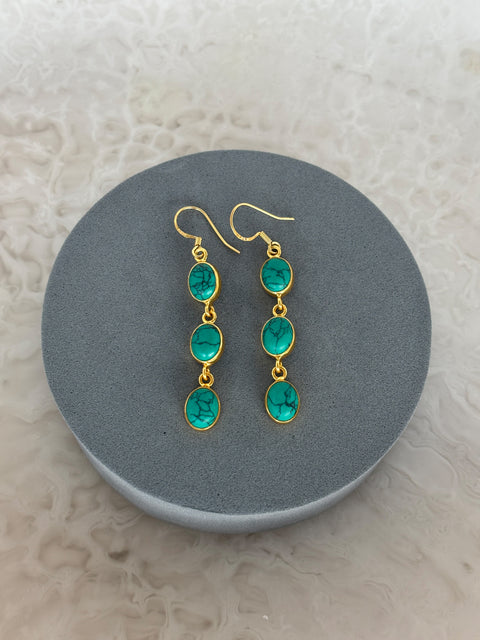Front Facing Shot of Zara Gold Plated Sterling Silver with 3 Chain Linked Turquoise Gems Earrings on Soft Pillow