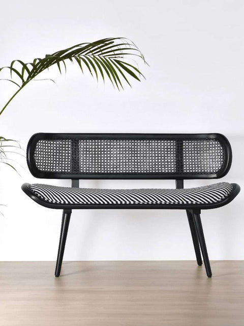 Lifestyle Shot of Amaya Teak Wood & Weaved Cane Handcrafted Bench in Black with Stripe Cushion